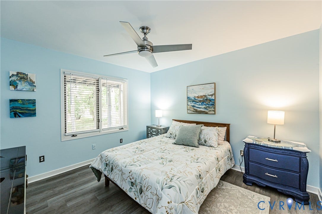 Ceiling fan with brushed nickel finish, two-pane window, wood-finish flooring, and light blue wall color