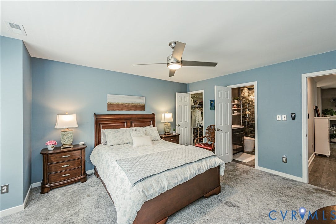 Sloped ceiling with an attached ceiling fan, light blue painted walls, gray carpet flooring, wood-finish bed frame, and white paneled interior doors