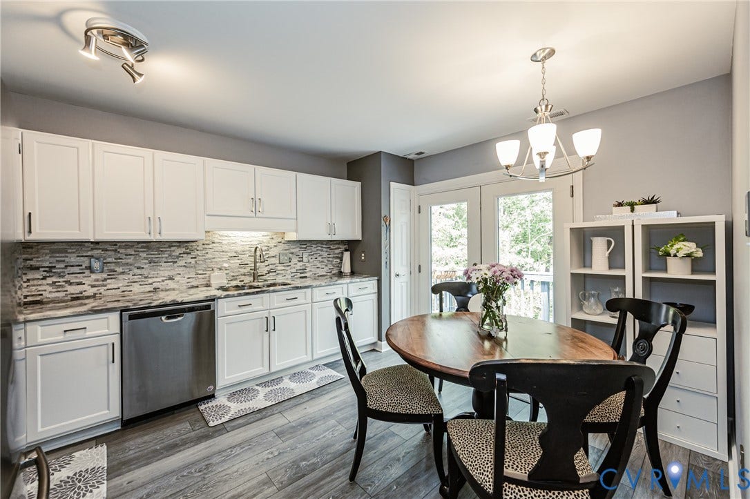 White cabinetry with dark hardware, stainless steel dishwasher, tile backsplash, wood-finish flooring, and double French doors to the exterior