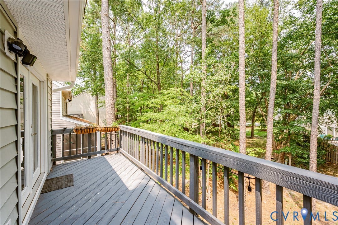Exterior deck with wood railing, natural wood-look flooring, and double-pane glass doors