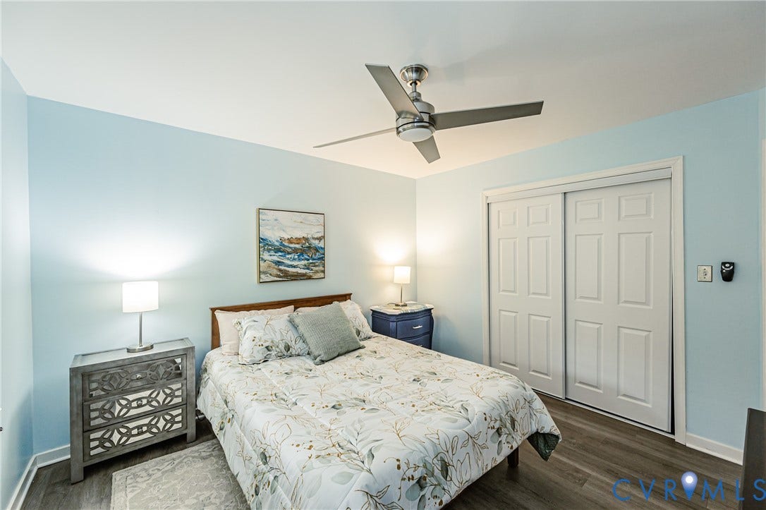 Wood-finish flooring, ceiling fan, white sliding closet doors, and light blue wall color