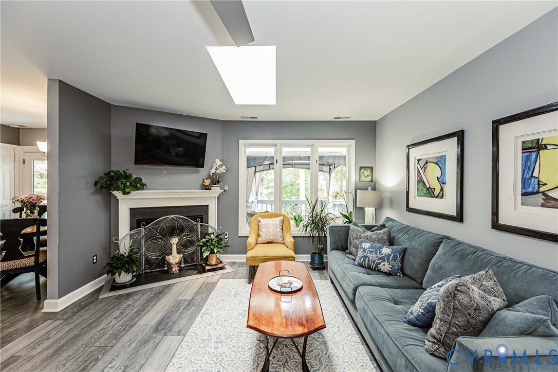 Living area featuring wood-finish flooring, a white mantel fireplace, and a large window with outdoor access