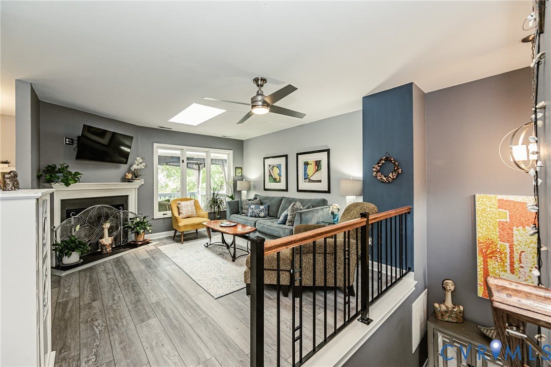 Living area with wood-finish flooring, a white fireplace with mantel, and a skylight
