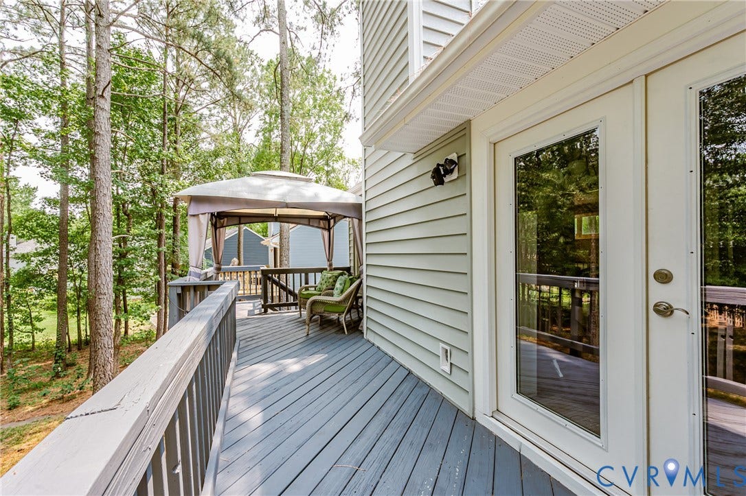 Expansive elevated wood deck with perimeter railing, featuring a dedicated gazebo area and direct entry via full-light double doors