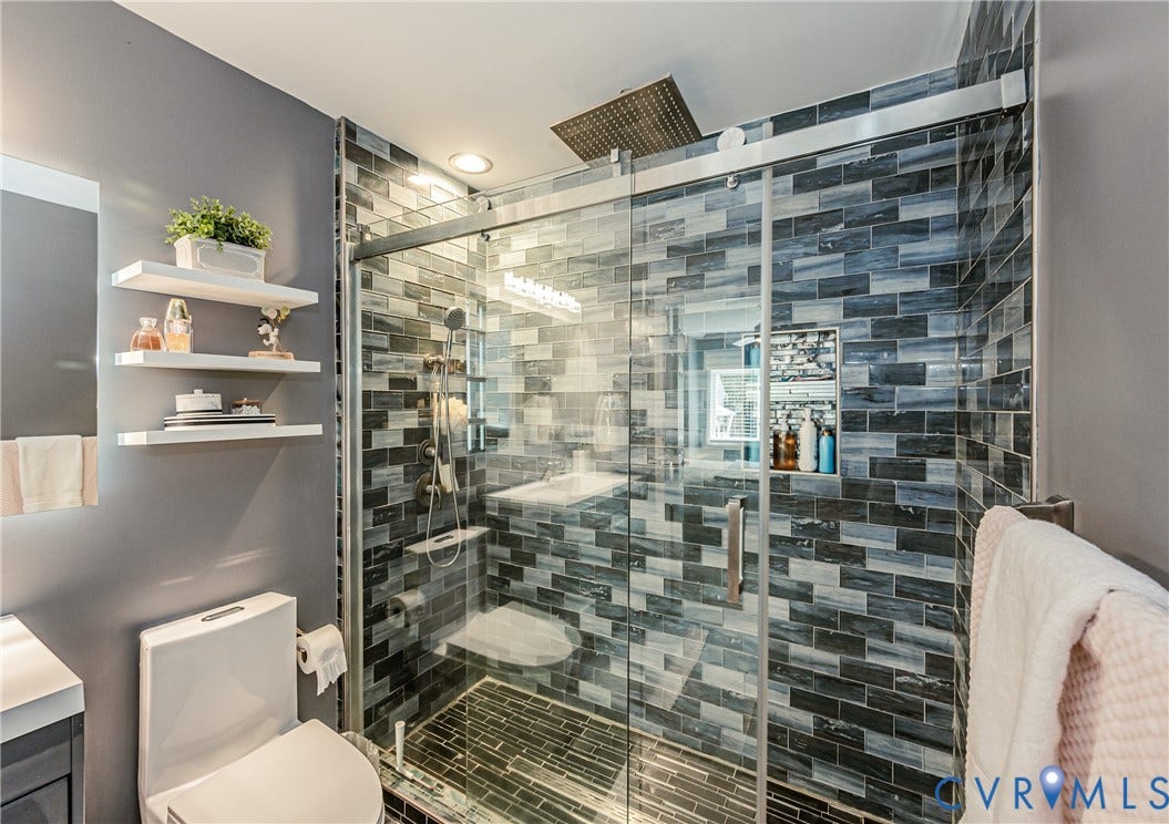 Glass-enclosed shower with mosaic tile surround, built-in shower niche, and rain showerhead