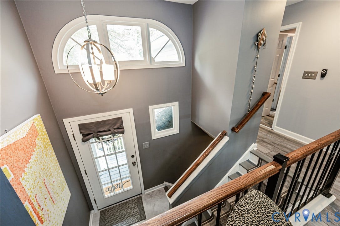 Entry foyer with high ceilings, arched transom window, and a contemporary chandelier