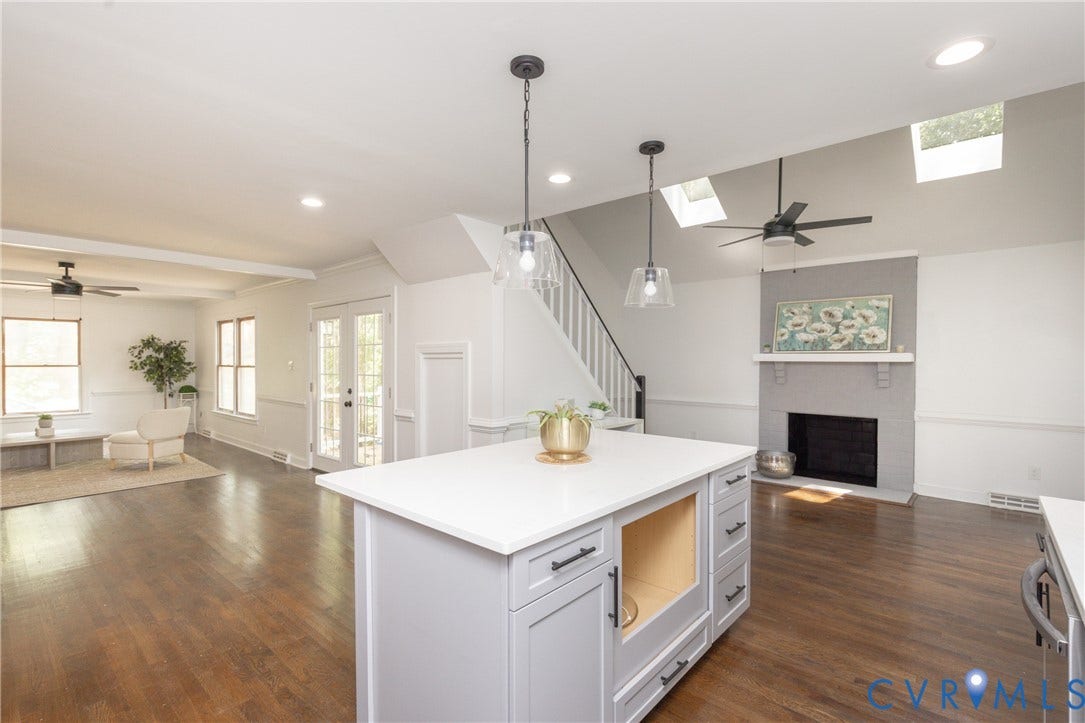 10541 Glencoe Road, Henrico, VA 23060 Open-concept living area featuring rich wood-finish flooring, a contemporary kitchen island with a light-colored countertop, and a fireplace with a mantel