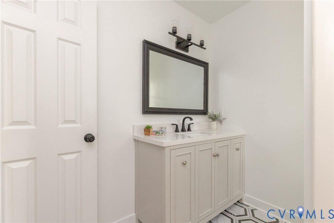 10541 Glencoe Road, Henrico, VA 23060 White paneled door with a black doorknob, light grey vanity with a white countertop, black framed mirror, and a black vanity light