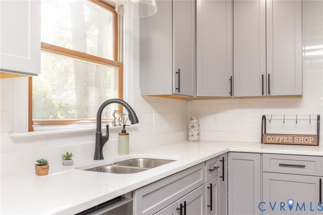 10541 Glencoe Road, Henrico, VA 23060 Light gray shaker-style cabinetry with matte black hardware, white countertop surfaces, and a stainless steel double basin sink with a gooseneck faucet