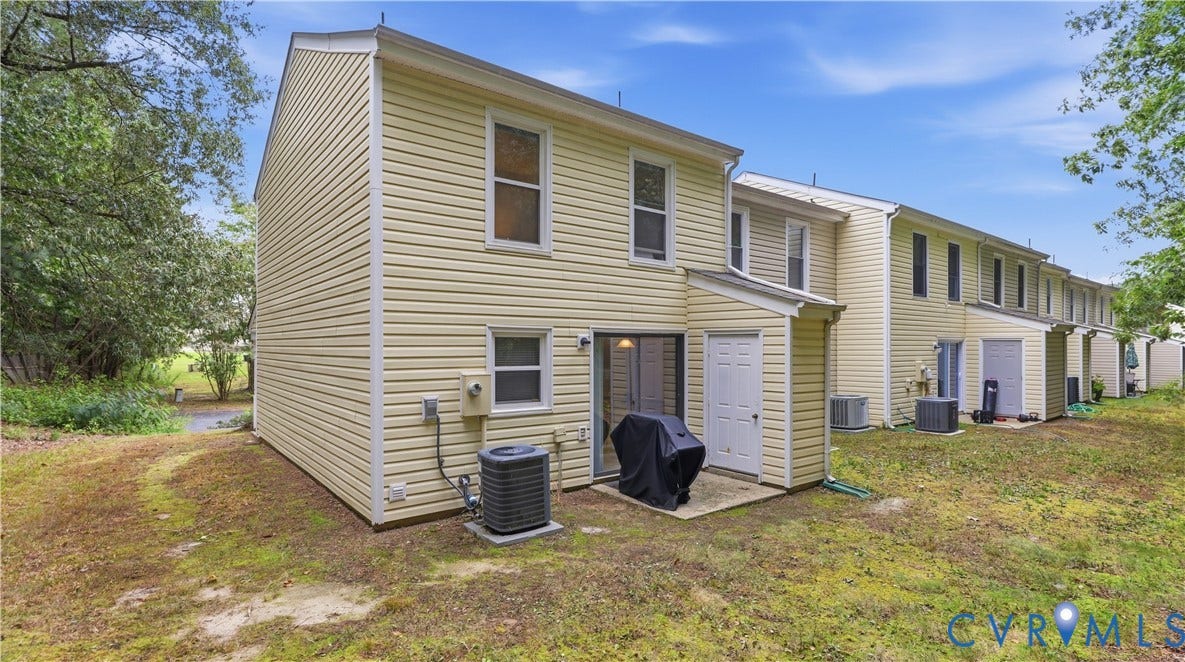 15253 Broadwater Circle, Chester, VA 23831 Rear exterior featuring yellow siding, a ground-level patio, and a sliding glass door