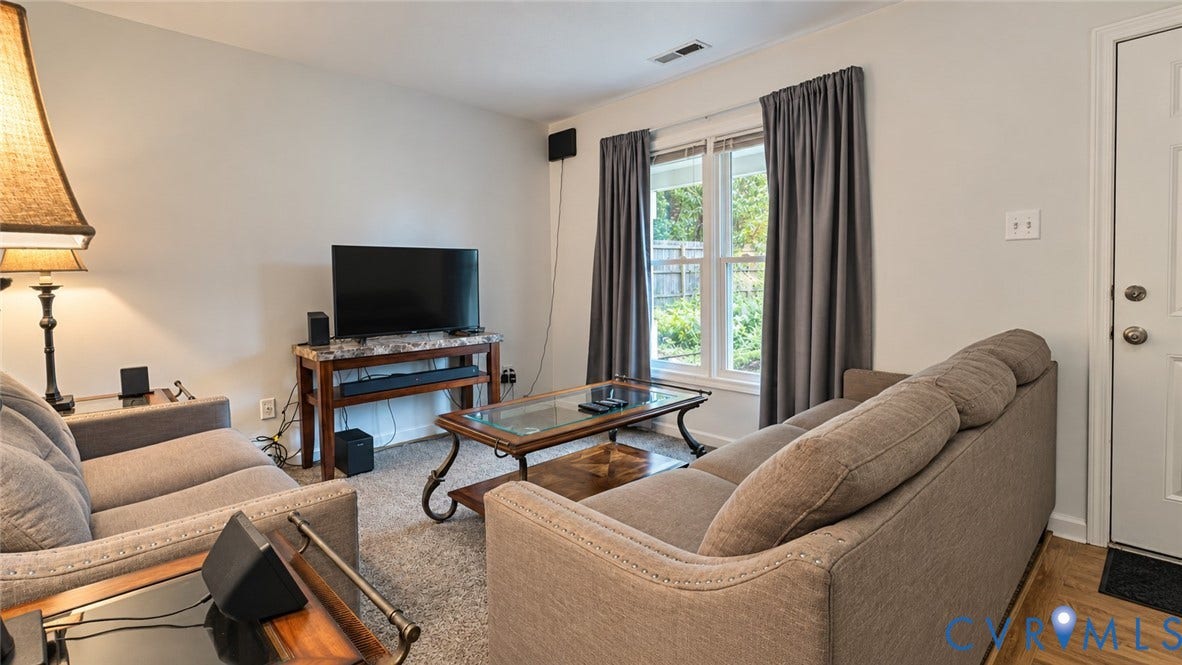 15253 Broadwater Circle, Chester, VA 23831 Carpeted living area with light-toned walls, double window with drapes, and a white entry door