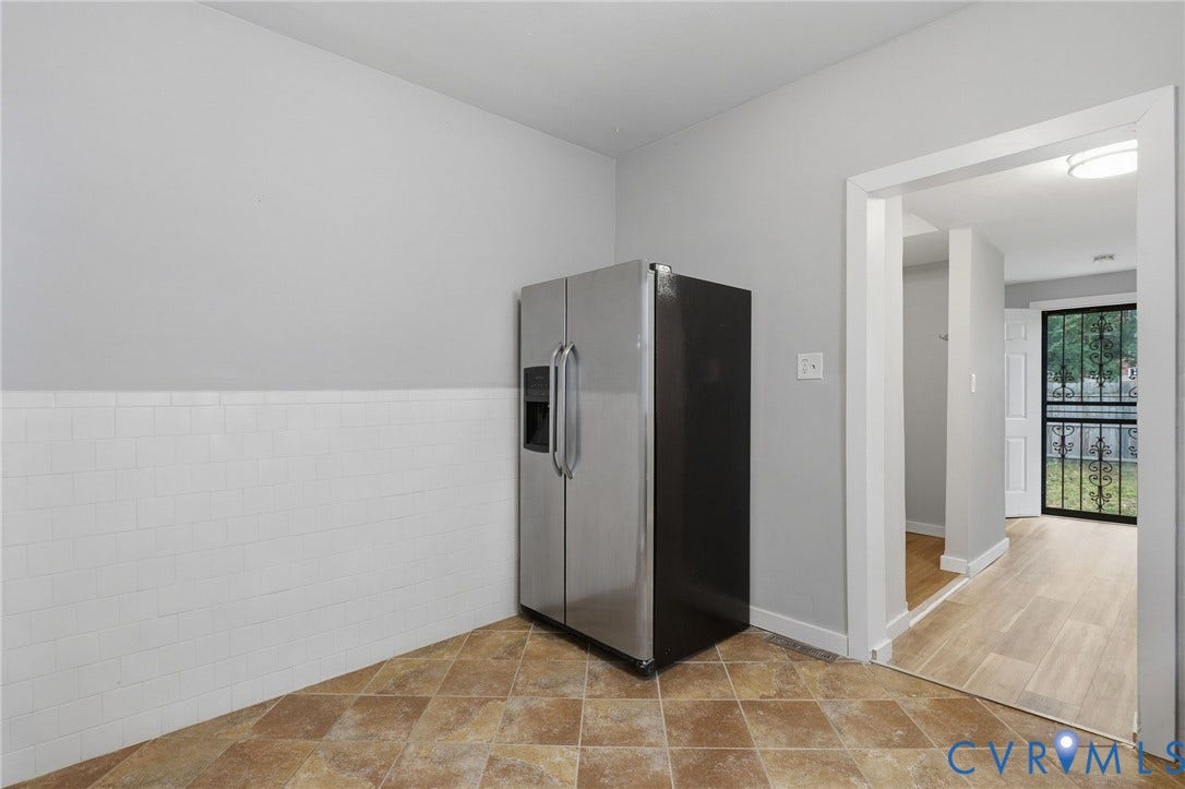 Kitchenette featuring a side-by-side refrigerator, white tile wainscoting, and patterned floor tiling