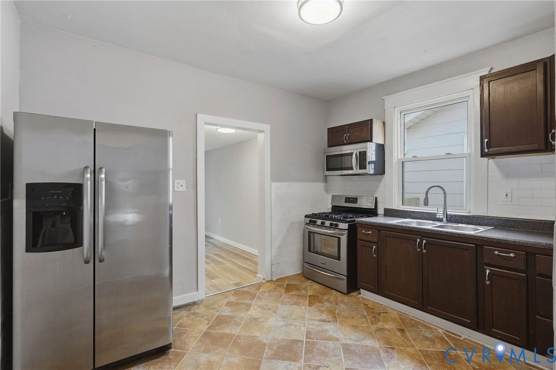 Kitchen featuring stainless steel appliances, dark wood-finish cabinetry, a dual basin sink, and a window above the sink