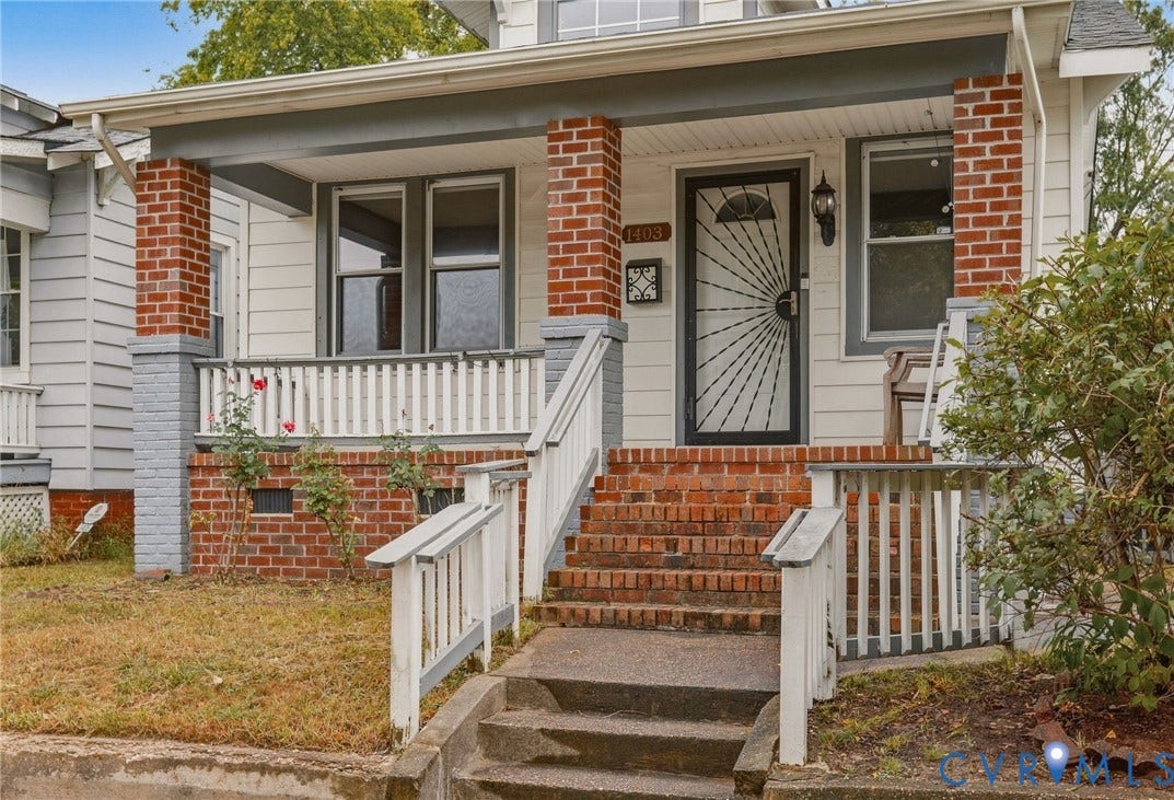 Brick foundation, covered front porch, brick columns, white siding, and a decorative security door