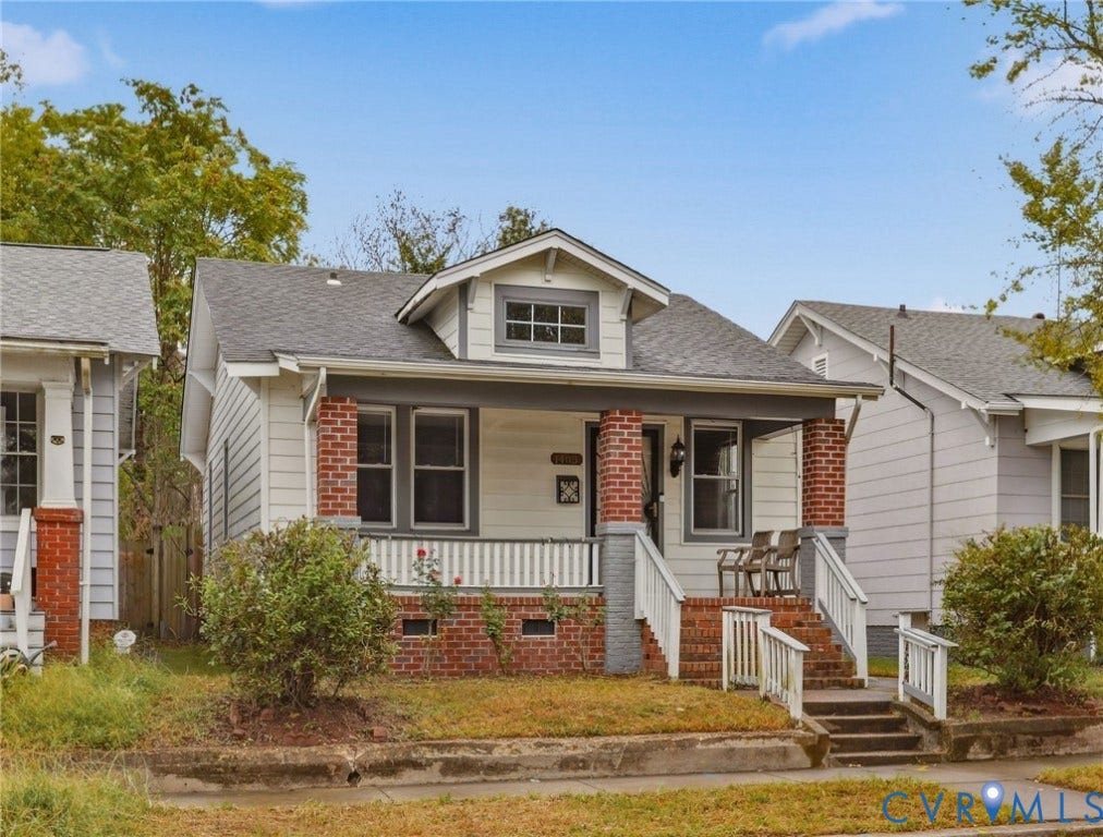 Craftsman-style exterior featuring a covered porch, brick columns, horizontal siding, and a gabled dormer