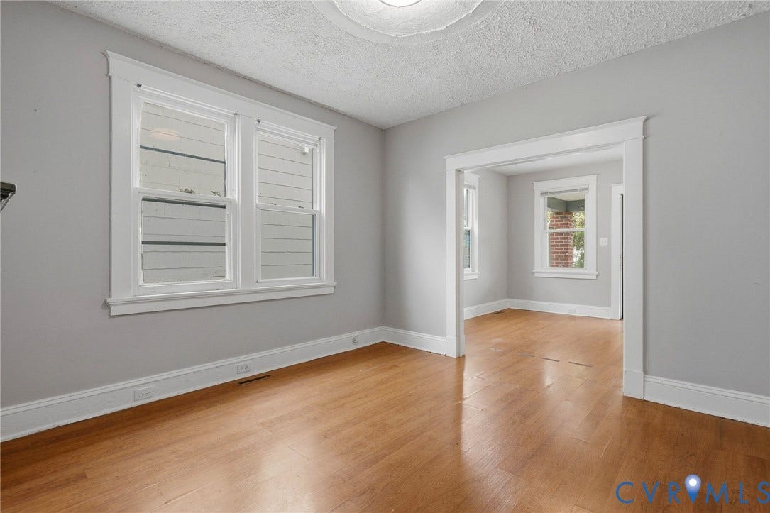 Hardwood flooring, light gray wall finishes, white trim, and a cased opening