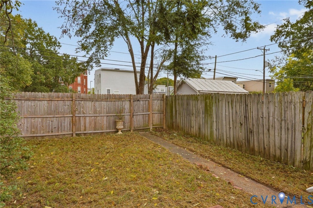 Fenced backyard featuring a walkway and mature perimeter trees
