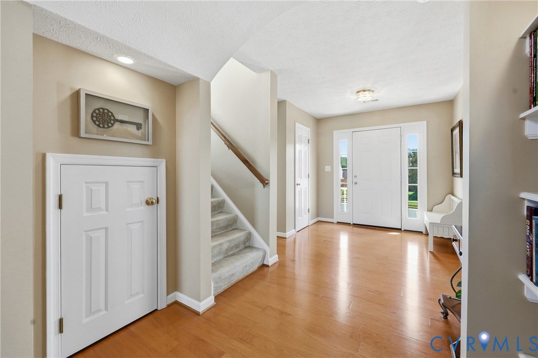 Hardwood flooring and a carpeted staircase create an inviting first impression upon entering the home