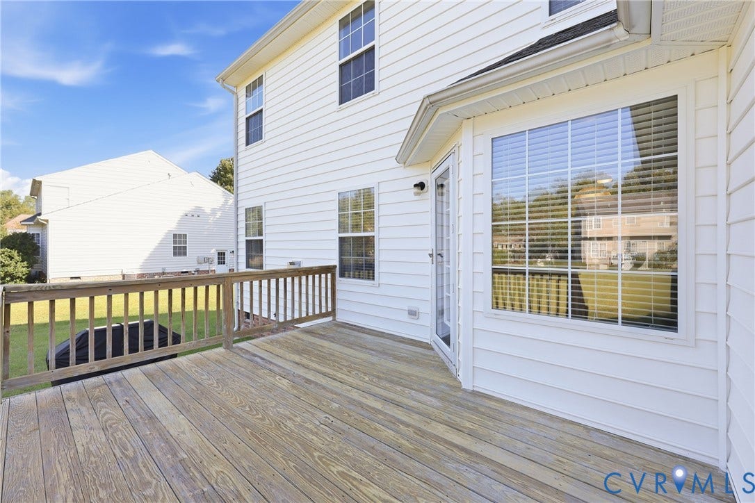 Rear wooden deck overlooking the expansive backyard, offering space for outdoor dining, relaxing, and entertaining.