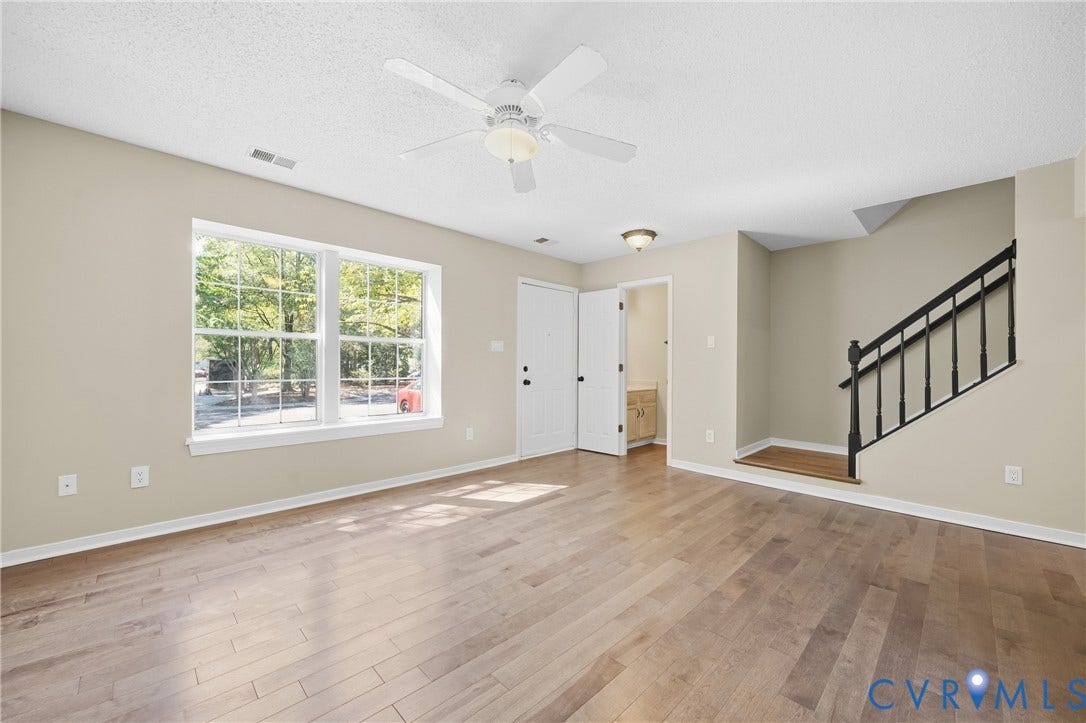 1852 Timberly Waye, Henrico, VA 23238 Hardwood-style flooring throughout, ceiling fan with integrated lighting, multiple windows, staircase with black banister, and interior doorway