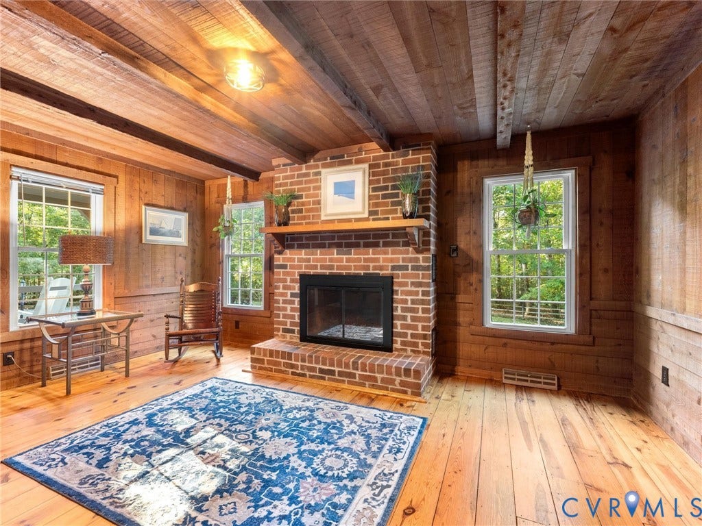 3801 Old River Trail, Powhatan, VA 23139 Full-room wood paneling, wood-plank ceiling with exposed beams, brick fireplace with a wood mantel, and wood-finish flooring