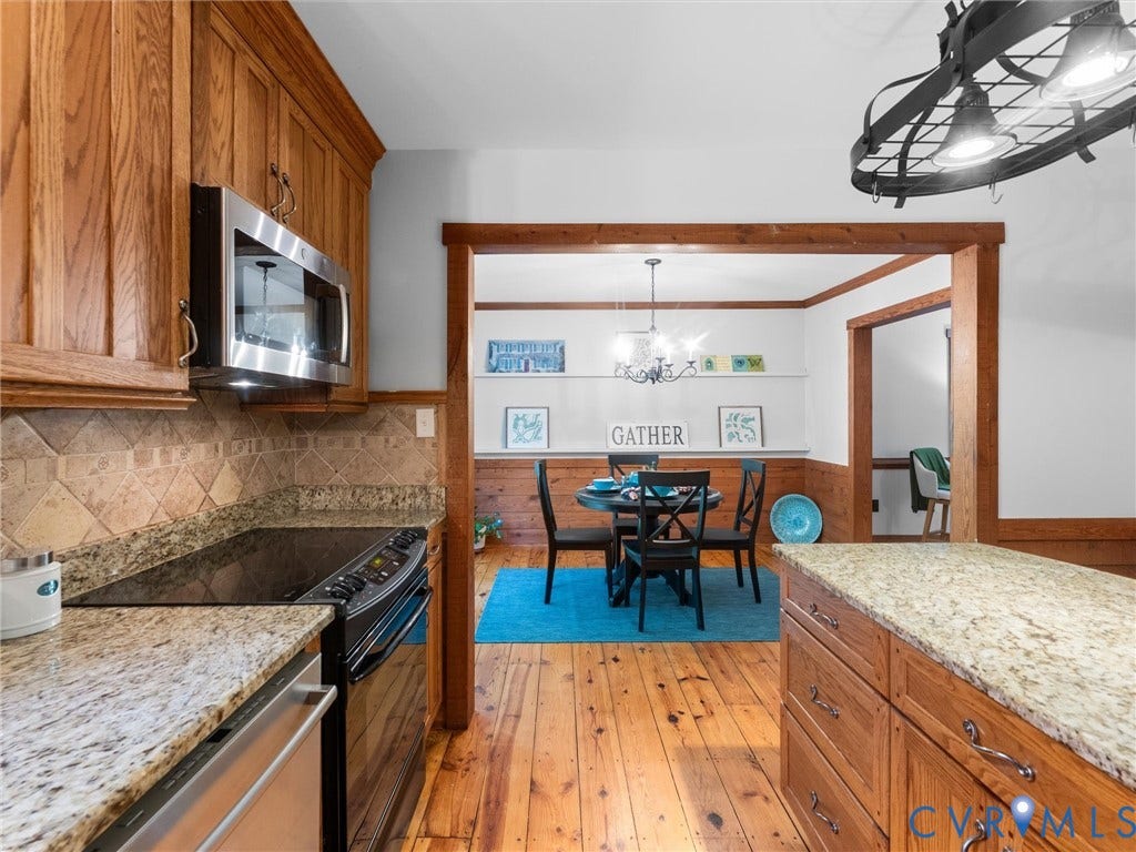 3801 Old River Trail, Powhatan, VA 23139 Kitchen featuring wood cabinetry, stone countertops, diagonal tile backsplash, and stainless steel appliances, with wide-plank wood flooring and wood-trimmed cased openings