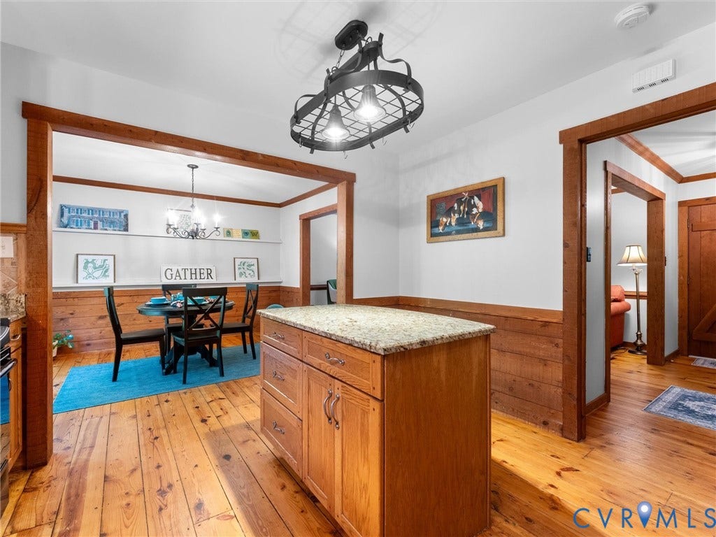 3801 Old River Trail, Powhatan, VA 23139 Custom wooden center island with stone countertop, natural wood-finish flooring, half-wall wainscoting, and decorative metal light fixture