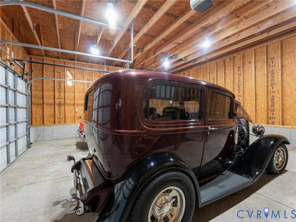3801 Old River Trail, Powhatan, VA 23139 Enclosed garage featuring exposed wood-stud walls, concrete flooring, overhead structural rafters, and sectional metal door