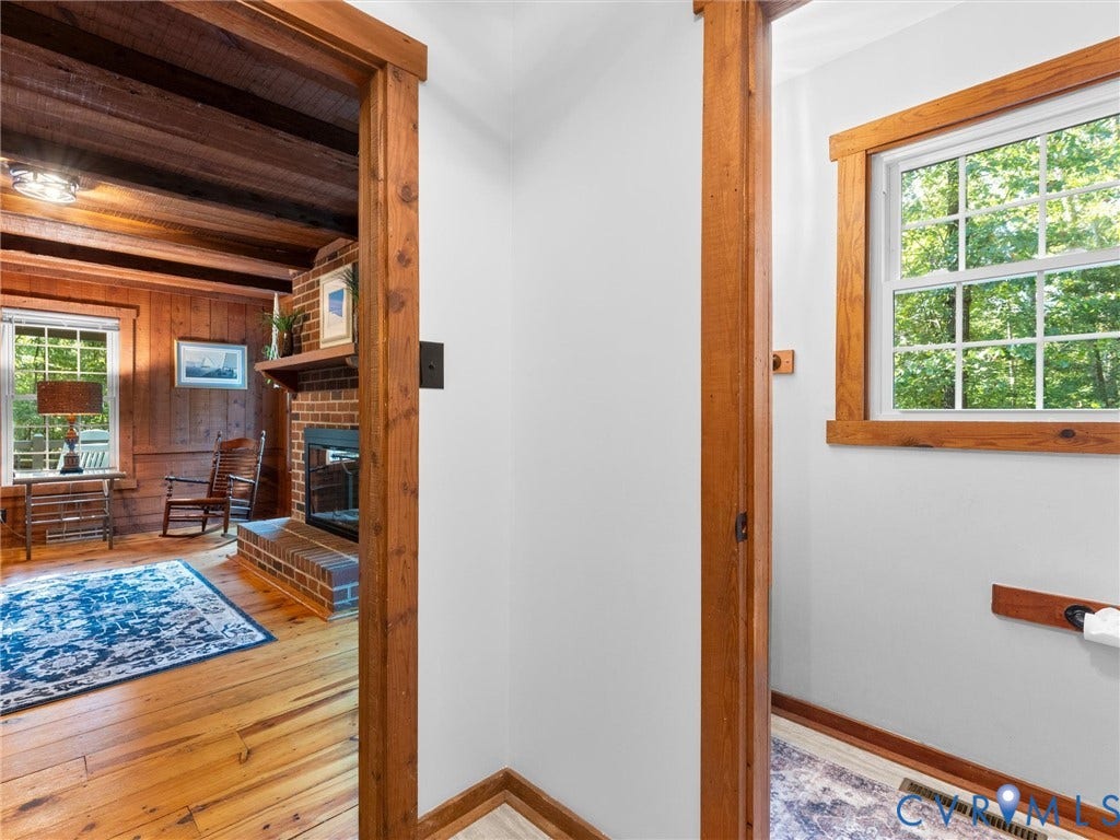 3801 Old River Trail, Powhatan, VA 23139 Interior featuring natural wood-finish flooring, exposed ceiling beams, a brick fireplace with a wood mantel, and thick-profile wood door and window casing