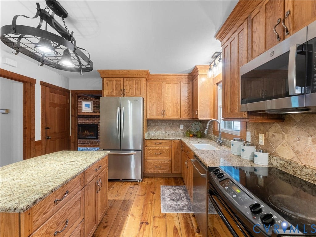 3801 Old River Trail, Powhatan, VA 23139 Kitchen featuring oak cabinetry, stone countertops, wide-plank wood flooring, stainless steel appliances, and a custom wrought-iron chandelier
