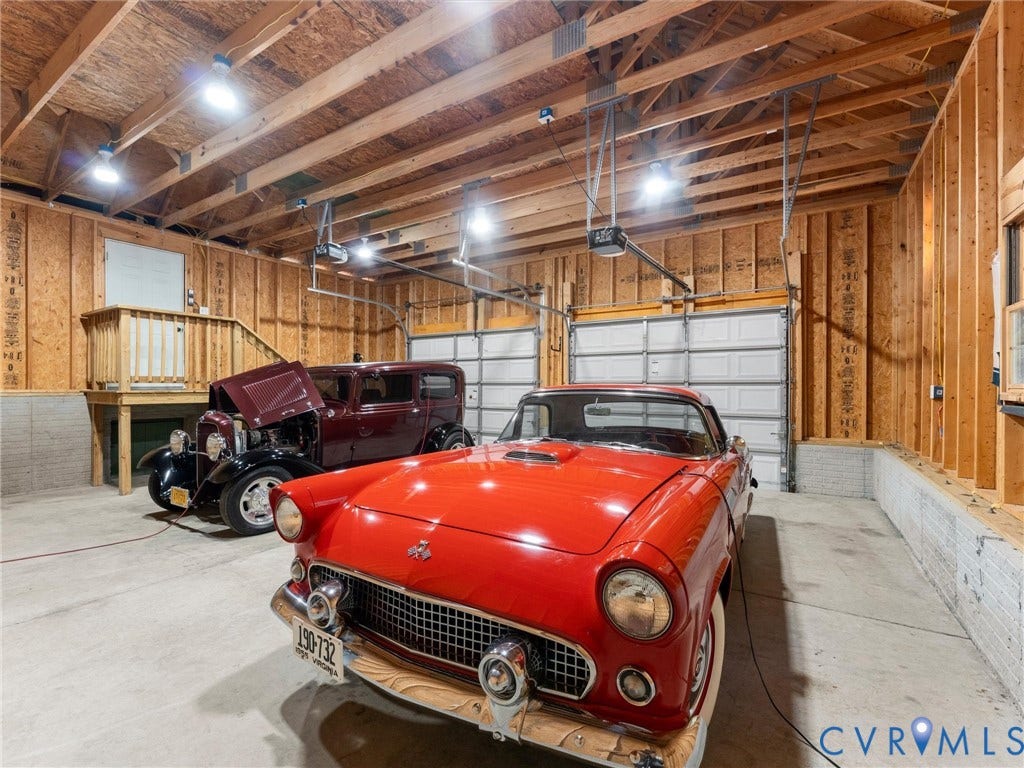 3801 Old River Trail, Powhatan, VA 23139 Multi-car garage featuring exposed wood stud framing, concrete flooring, two overhead garage doors, and an elevated wood platform with railing