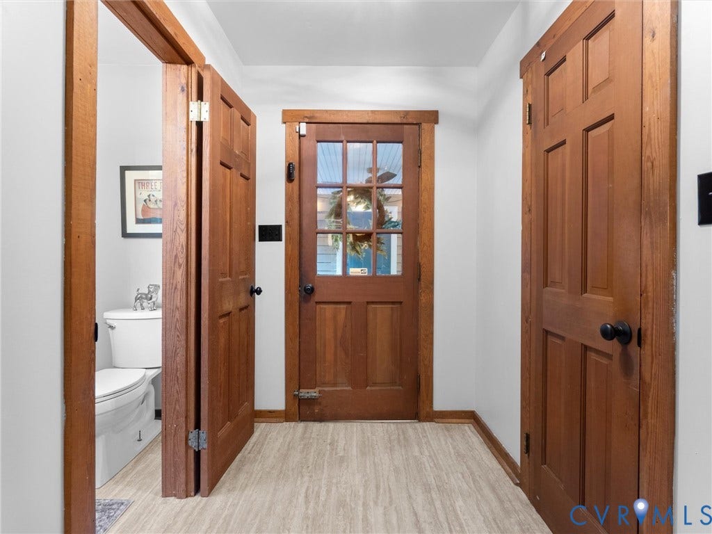 3801 Old River Trail, Powhatan, VA 23139 Charming hallway showcasing rich wood-finish doors with six-panel detailing, wood-finish flooring throughout, and abundant natural light from a central entrance door featuring multiple panes