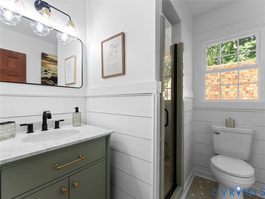 3801 Old River Trail, Powhatan, VA 23139 Bathroom featuring olive green vanity with brass-finish hardware, stone-composite countertop, shiplap wall treatment, glass-enclosed shower, and multi-light vanity fixture