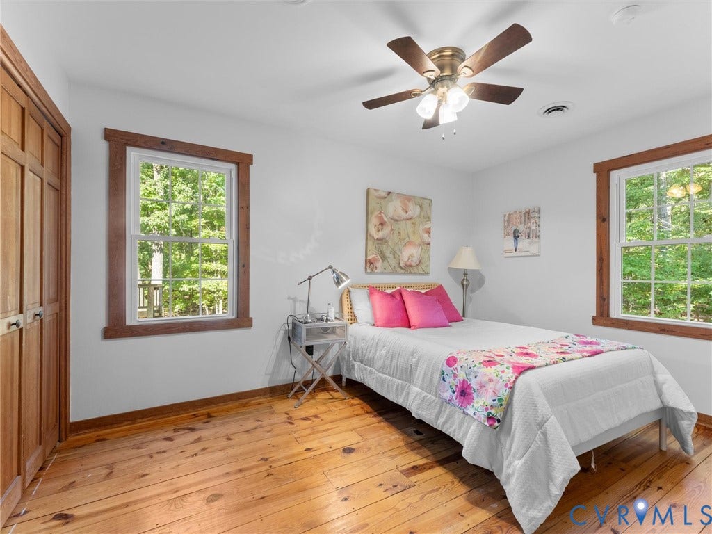 3801 Old River Trail, Powhatan, VA 23139 Room featuring solid wood-finish flooring, dual windows with wood trim, built-in wooden closet doors, and a ceiling fan with integrated lighting