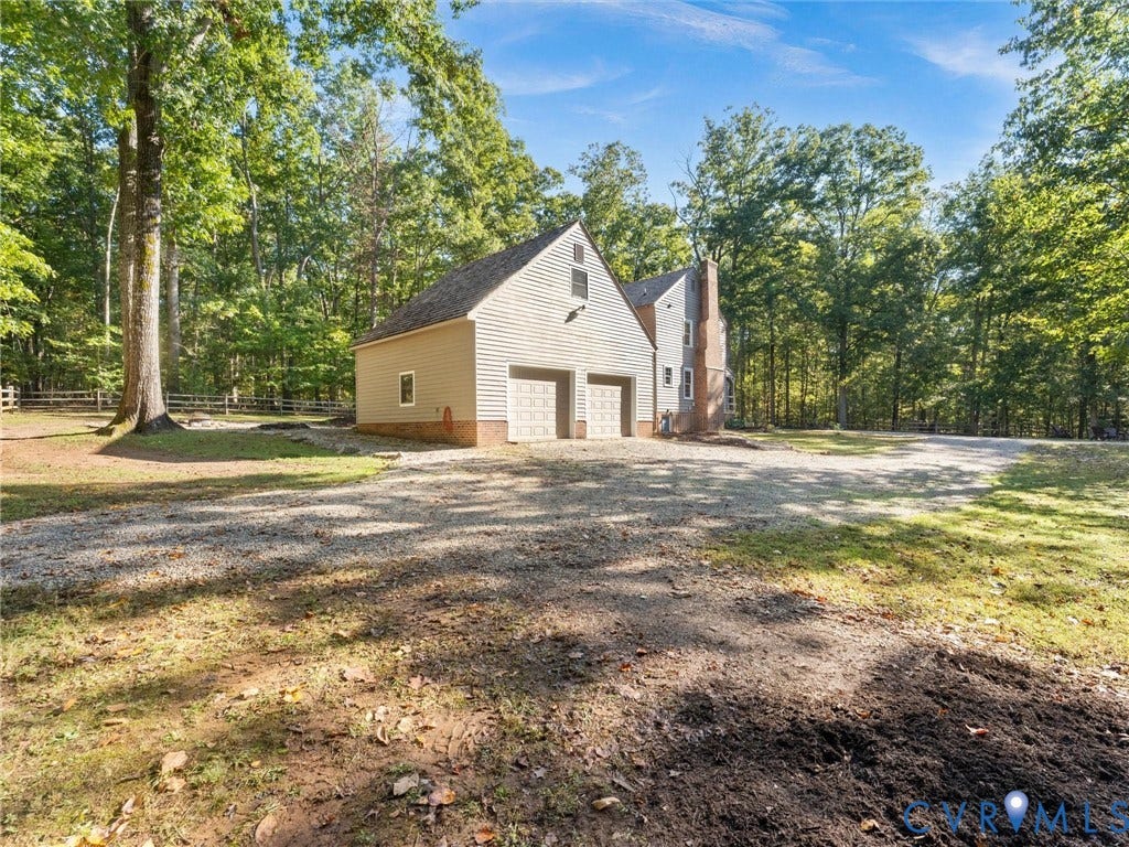 3801 Old River Trail, Powhatan, VA 23139 Two-car garage featuring vinyl siding, brick foundation, gravel driveway, and surrounding mature timber