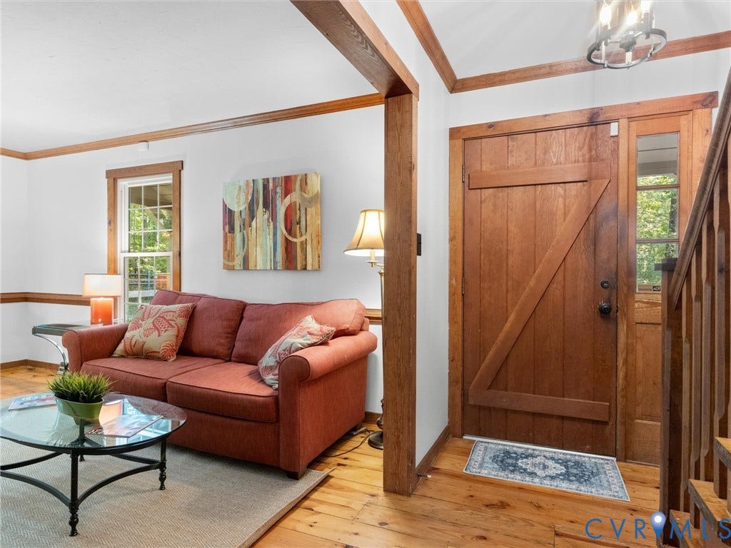 3801 Old River Trail, Powhatan, VA 23139 Natural wood-finish flooring, custom plank-style entry door with side light, wood trim detailing, and open-plan structural beams