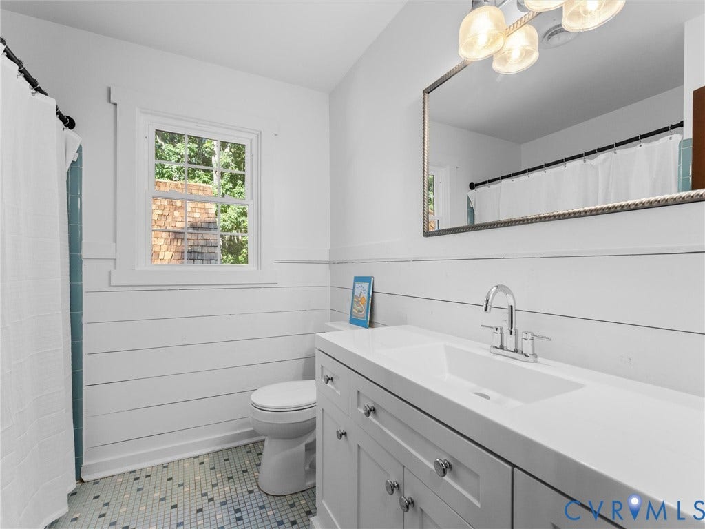 3801 Old River Trail, Powhatan, VA 23139 Bathroom featuring white shiplap walls, a single-sink vanity with a solid-surface countertop, a rectangular undermount sink, multi-tone tiled flooring, and a framed wall mirror