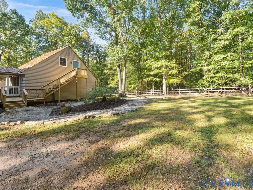 3801 Old River Trail, Powhatan, VA 23139 Expansive lawn with mature trees, timber-style exterior siding, exterior wooden staircase, and multi-level wooden decking