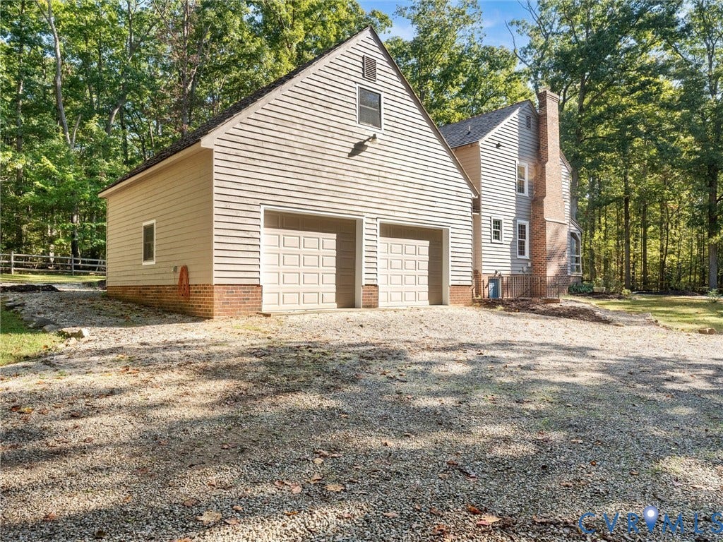 3801 Old River Trail, Powhatan, VA 23139 Two-car garage with horizontal siding and brick foundation, exterior masonry chimney, and gravel driveway