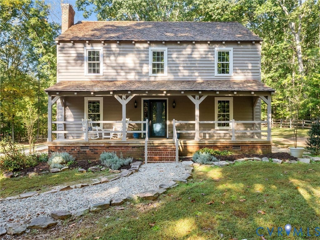 3801 Old River Trail, Powhatan, VA 23139 Two-story residence featuring horizontal lap siding, a cedar shake roof, a covered front porch with timber-frame accents, a brick foundation, and a stone-lined gravel path
