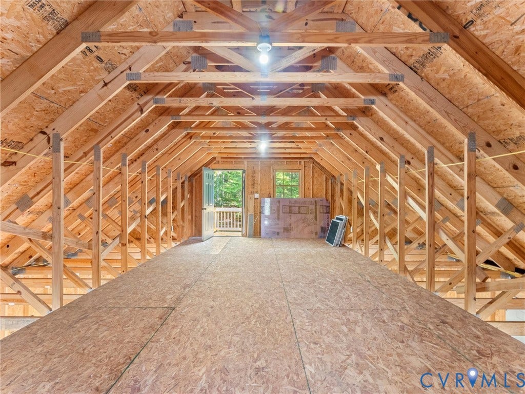 3801 Old River Trail, Powhatan, VA 23139 Unfinished attic space featuring exposed wood-frame trusses, plywood flooring, and an exterior door providing outdoor access