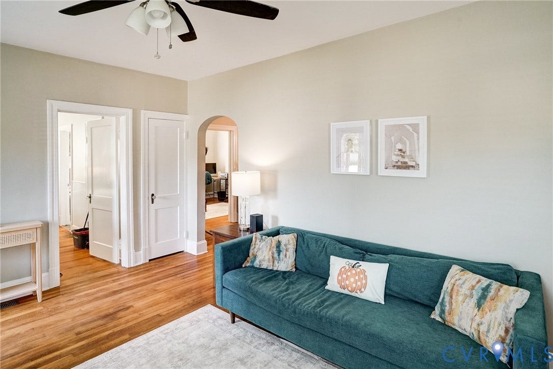 Hardwood flooring throughout, ceiling fan with integrated lighting, arched doorway, and light wall color