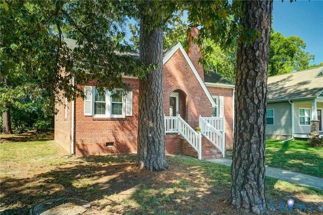 Brick exterior featuring a gabled roofline, decorative white shutters, and an arched entry