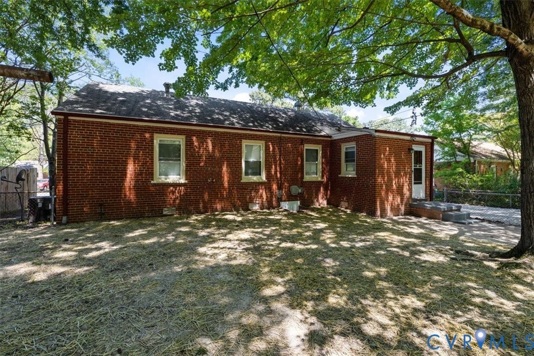 1215 Starling Drive, Henrico, VA 23229 Brick exterior residence with a shingle roof, multiple windows with light-colored trim, and a rear entry door with steps