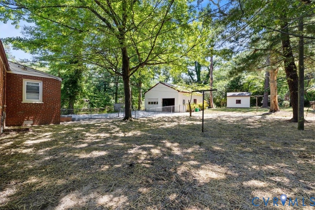 1215 Starling Drive, Henrico, VA 23229 Spacious rear yard with mature trees, a detached two-car garage, and an additional auxiliary building
