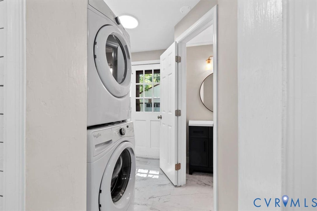 1215 Starling Drive, Henrico, VA 23229 Stackable washer and dryer, white paneled door, black vanity, round mirror, and wall-mounted light fixture