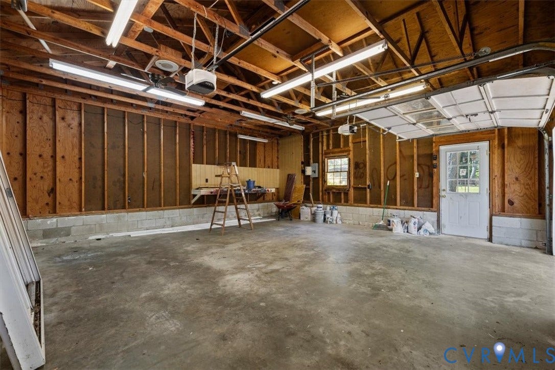 1215 Starling Drive, Henrico, VA 23229 Exposed wood beam ceiling, concrete flooring, fluorescent lighting, service door with glass panes, and a window with muntins