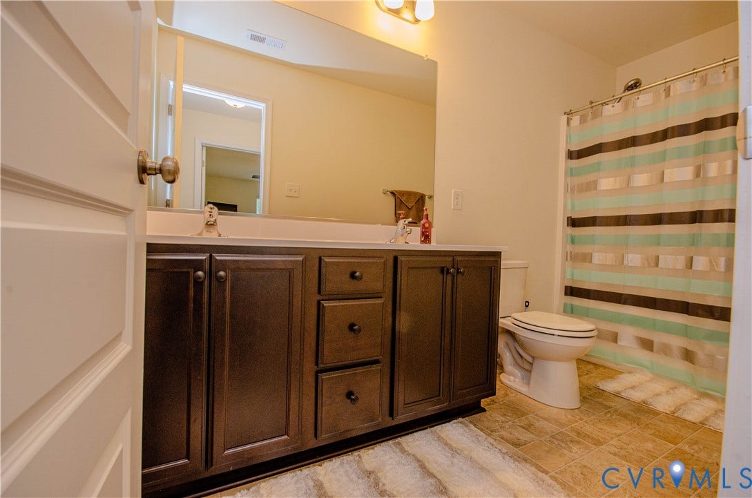 Dual vanity with dark wood-finish cabinetry, white countertop, and integrated sinks