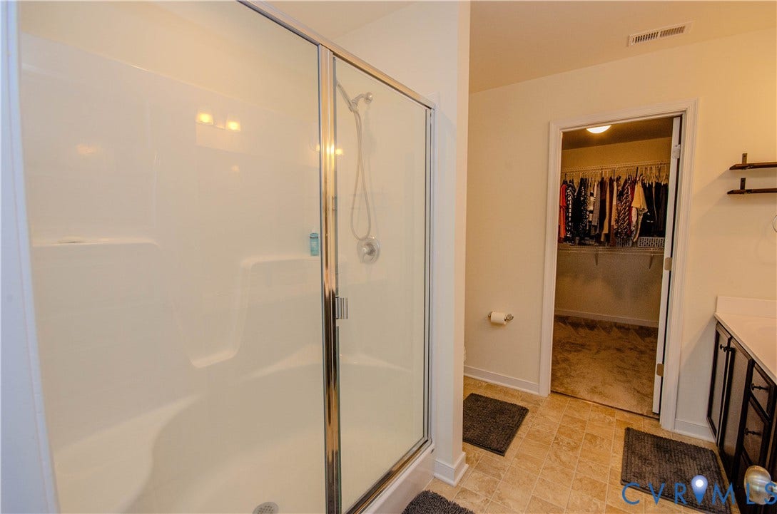 Primary bedroom bath ensuite with shower with glass enclosure, handheld showerhead, and walk-in closet