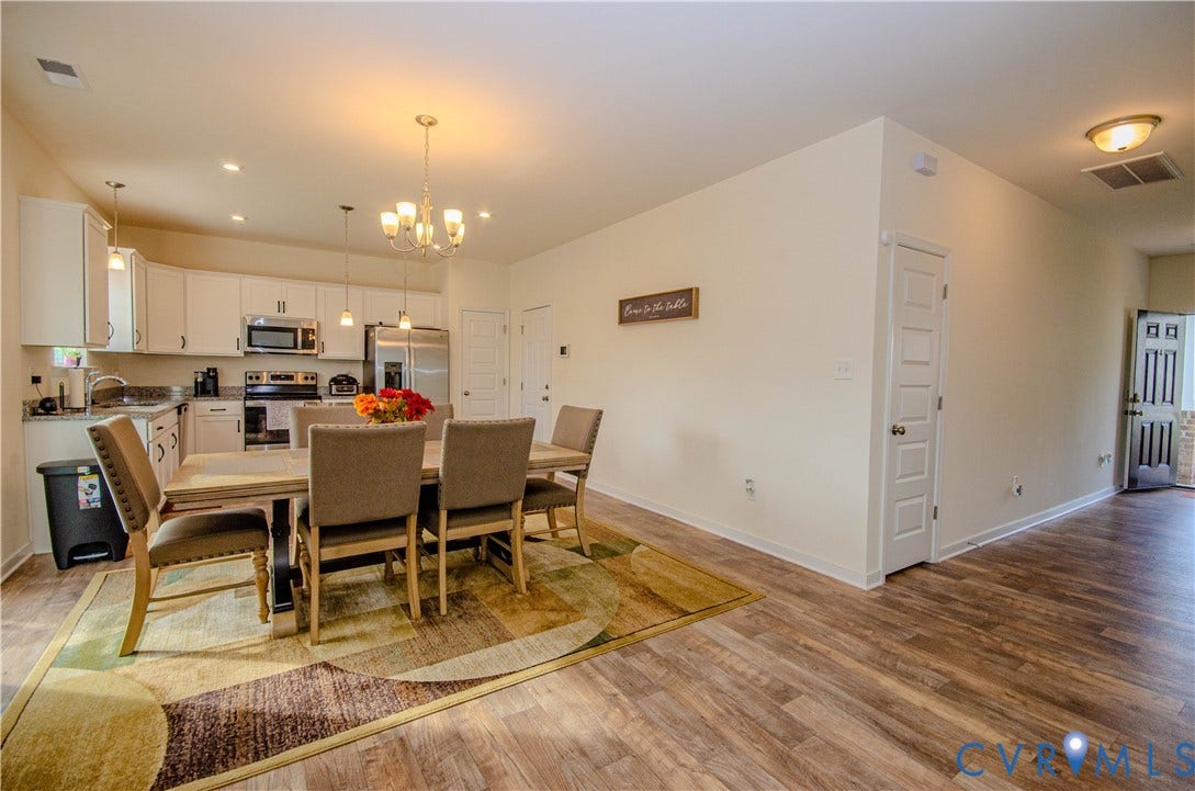 Open-concept kitchen and dining area featuring white cabinetry, stainless steel appliances, pantry, and recessed lighting.